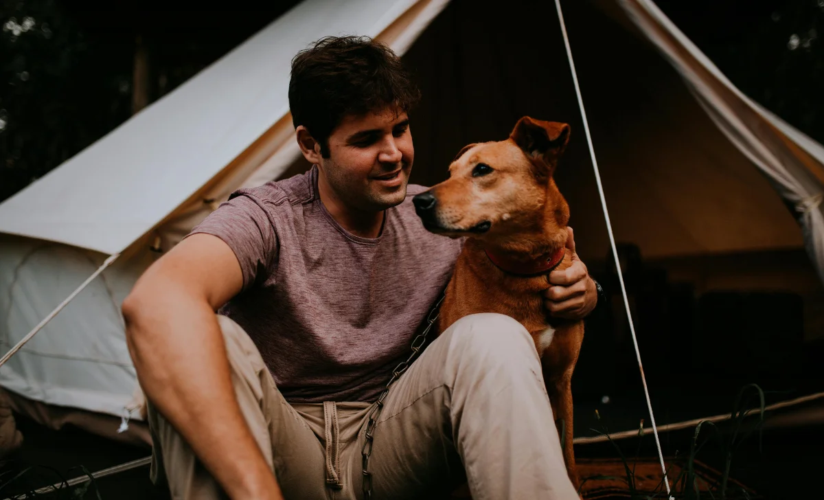 a man camping with a dog