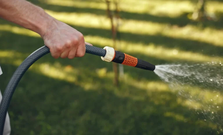 a man watering grass with a hose
