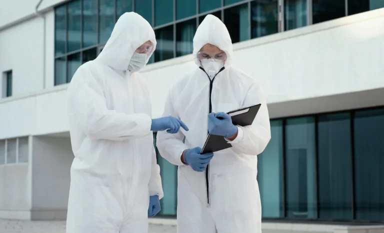 two people wearing white protective suits with report in hand
