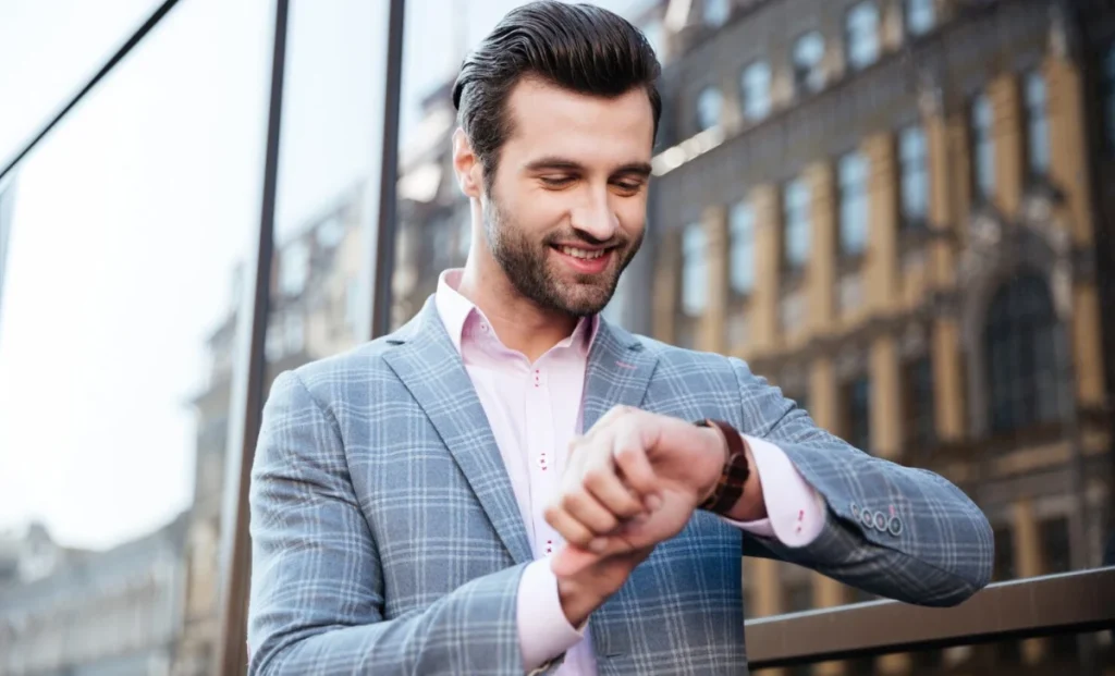 a man smiling and looking at his watch