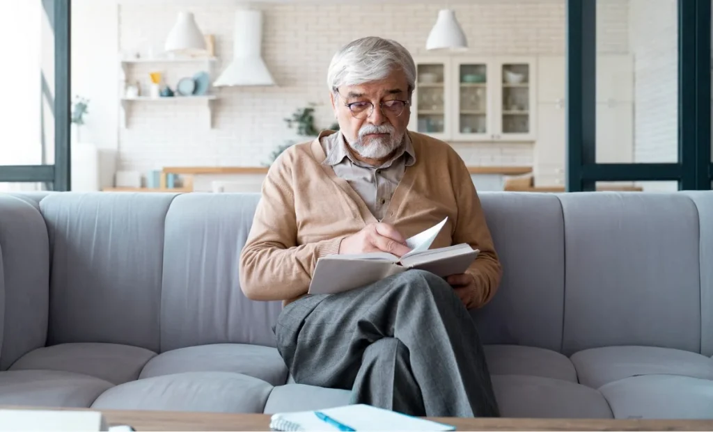 a senior man reading a book at home