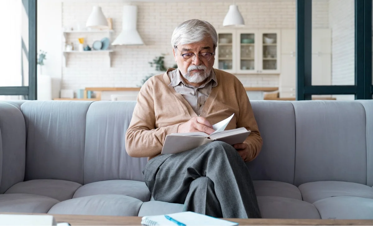 a senior man reading a book at home