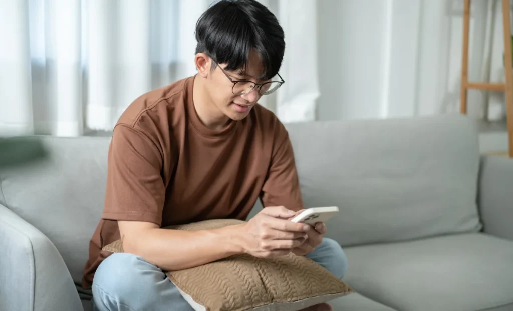 a young man using phone while sitting on a sofa