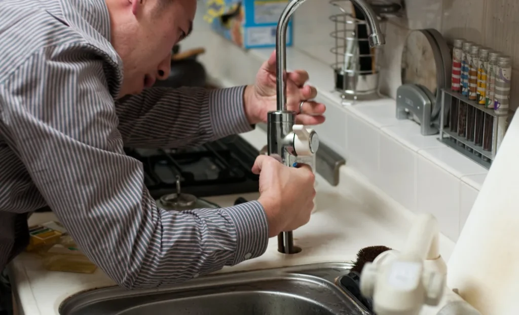 a plumber repairing a kitchen sink faucet