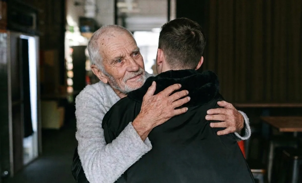 a young man hugging a senior man