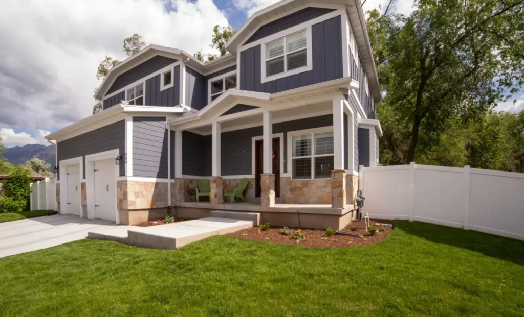 Modern two-story home with dark siding, stone accents, and manicured lawn