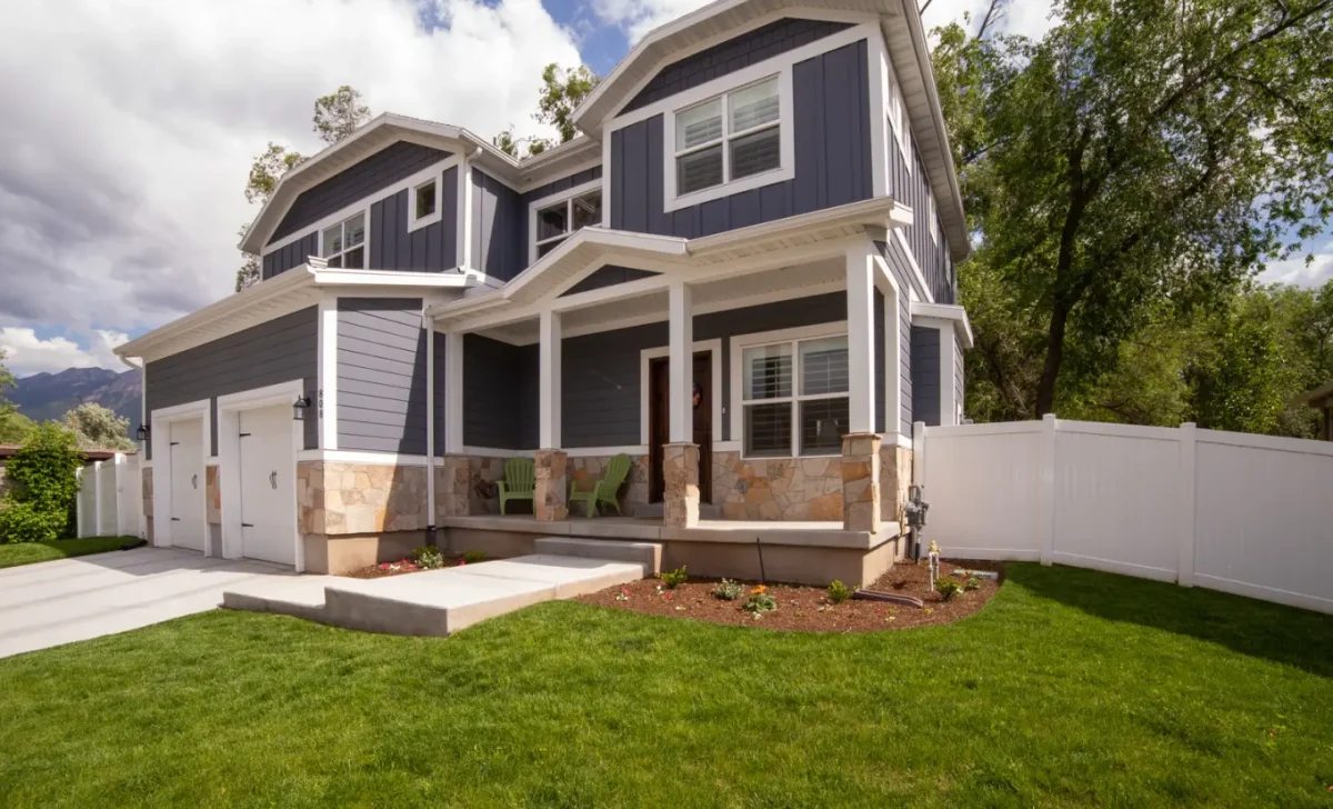 Modern two-story home with dark siding, stone accents, and manicured lawn
