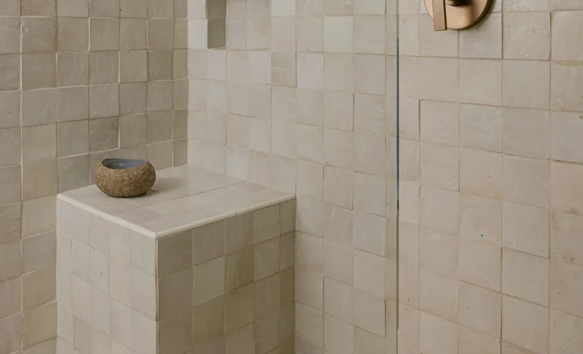 Moroccan zellige tile shower with brass fixtures and built-in niche shelves