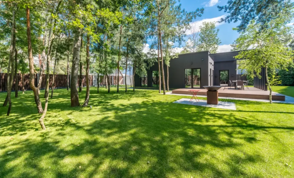 Modern house with a landscaped garden, green lawn, mature trees and a wooden deck
